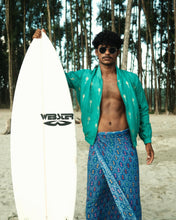Load image into Gallery viewer, Man holding a surfboard with a brand logo on a beach