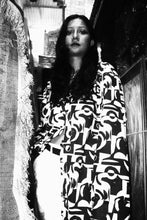 Load image into Gallery viewer, Person wearing a patterned dress sitting on a couch.