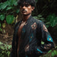 Man wearing a black embroidered jacket in a forest setting