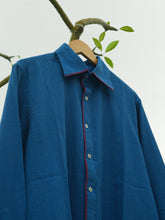 Load image into Gallery viewer, Blue shirt with red accents on a hanger against a white background
