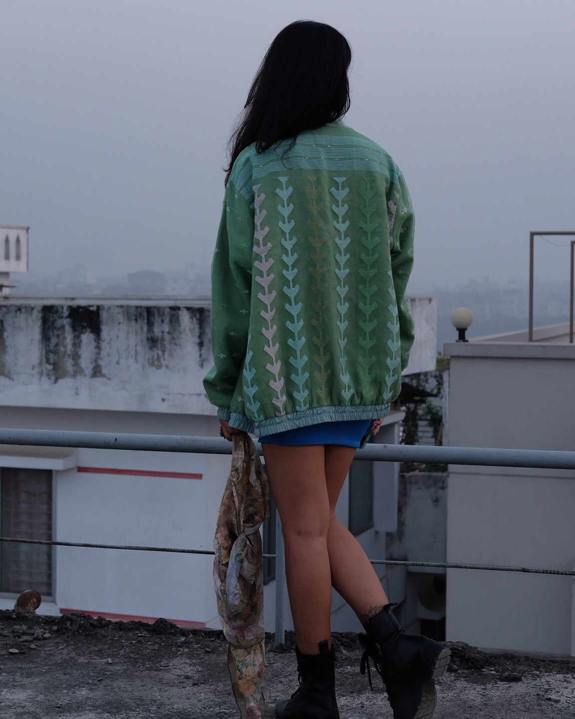 Person wearing a green patterned sweater standing on a snowy surface.