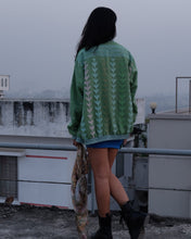 Load image into Gallery viewer, Person wearing a green patterned sweater standing on a snowy surface.
