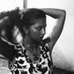 Black and white photo of a person wearing a patterned dress.