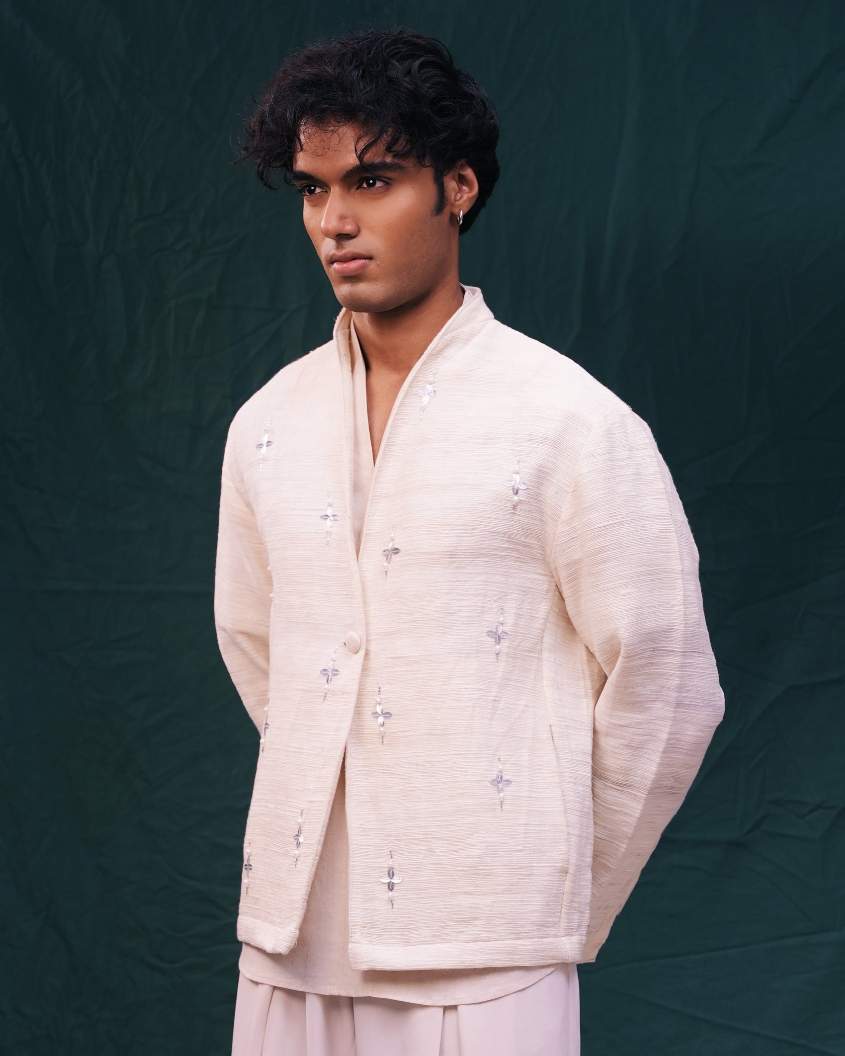 Man wearing a light-colored traditional outfit against a dark background