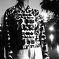 Black and white patterned cropped jacket worn by a person with a reflective surface below