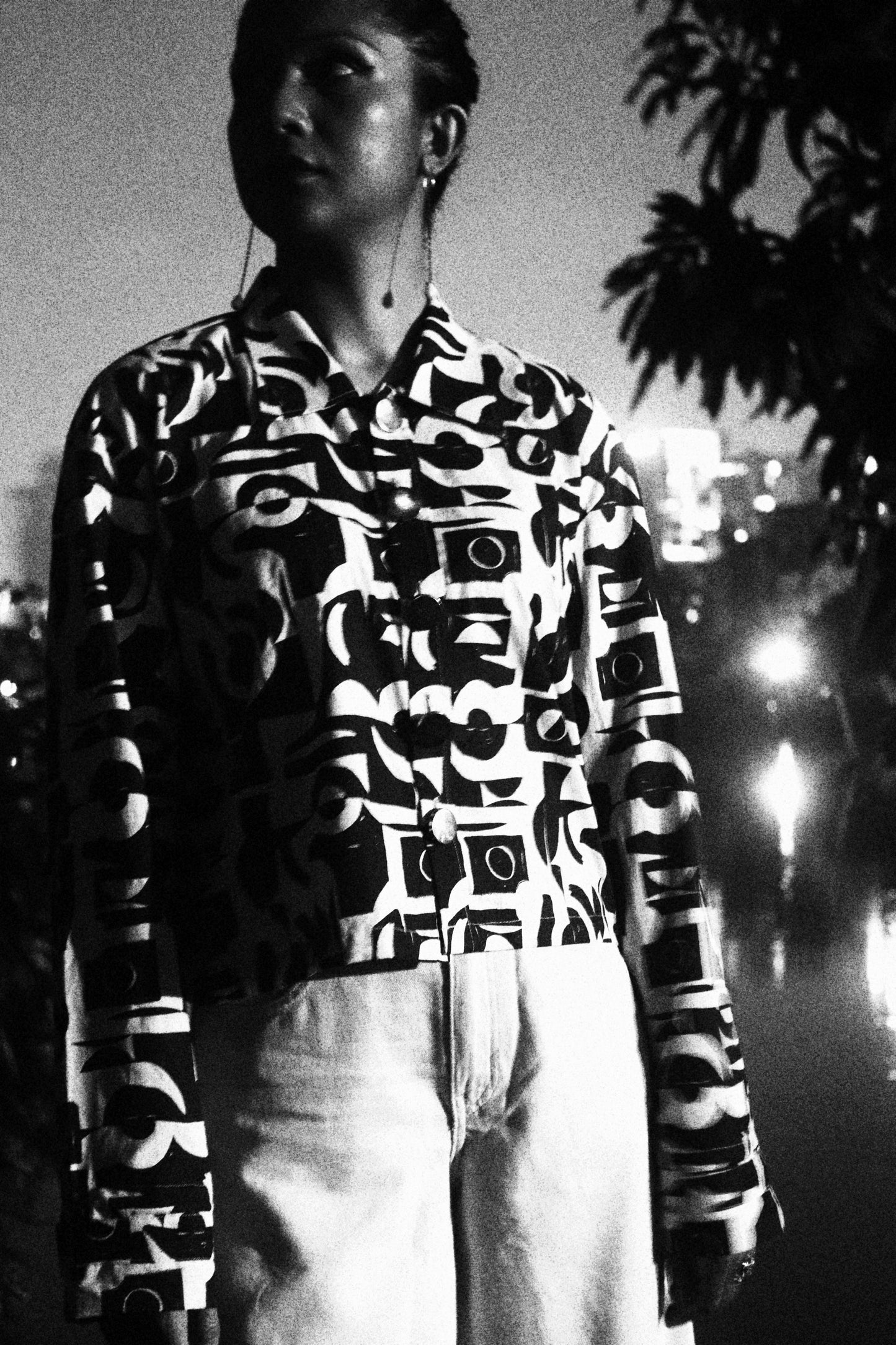 Black and white patterned cropped jacket worn by a person with a reflective surface below