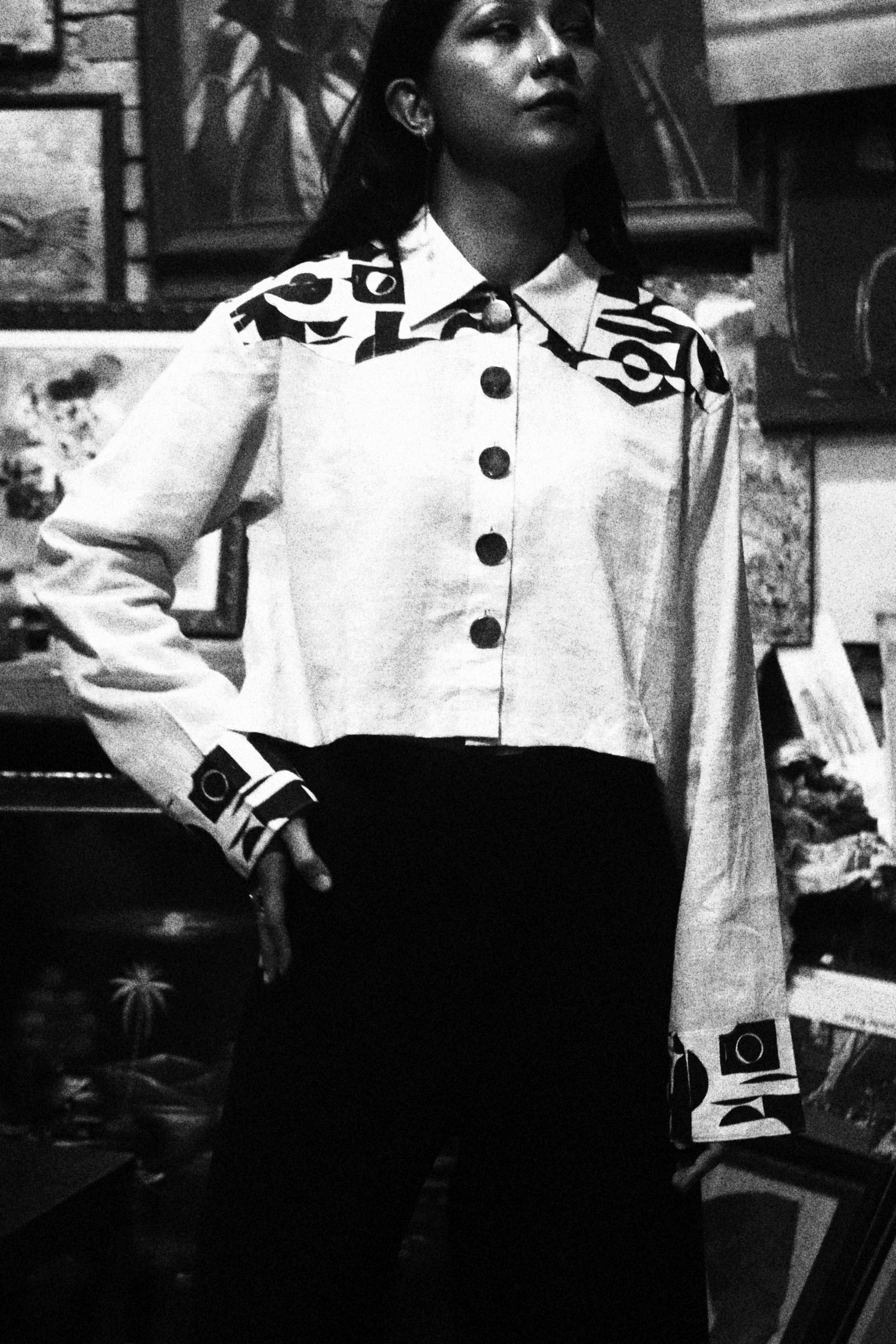 Person wearing a white jacket with black text sitting on a chair indoors.