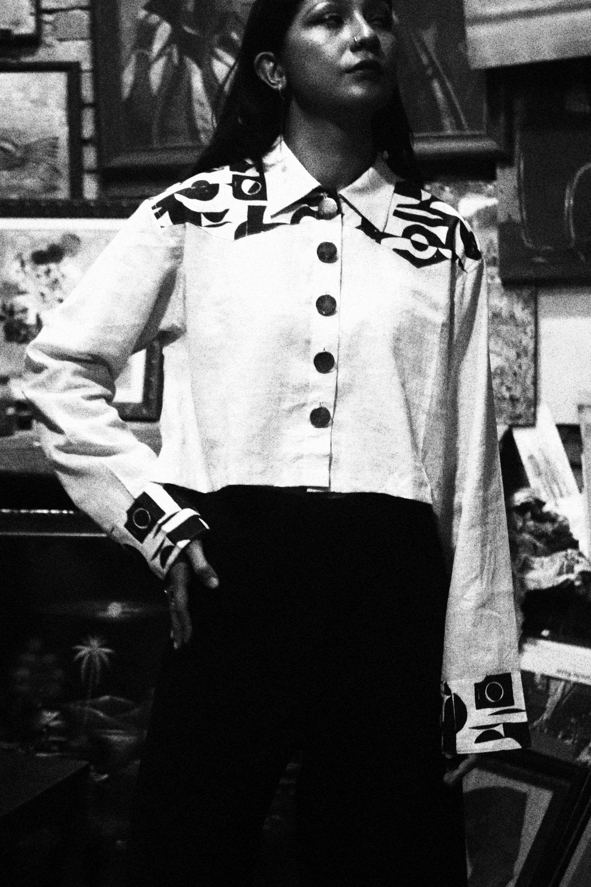 Person wearing a white jacket with black text sitting on a chair indoors.