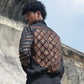 Person wearing a patterned jacket standing against a stone wall with a blue sky background