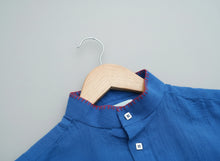Load image into Gallery viewer, Blue shirt on a wooden hanger against a grass background
